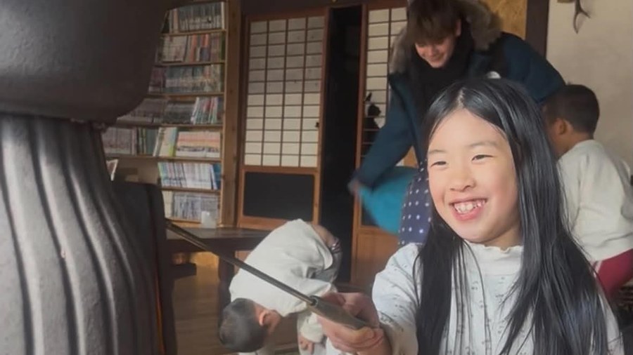 薪ストーブのそばで笑う子ども